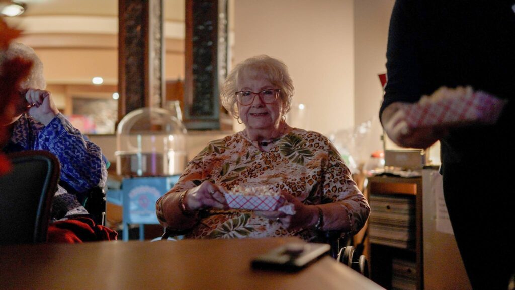 A woman goes to movie night at a skilled nursing facility