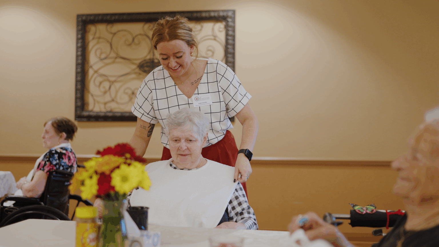 A woman is assisted by a nurse at a skilled nursing care facility